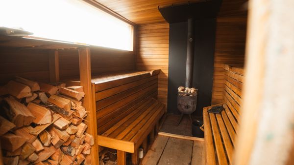 Warm wooden sauna interior with benches and fireplace, offering a relaxing and inviting atmosphere.