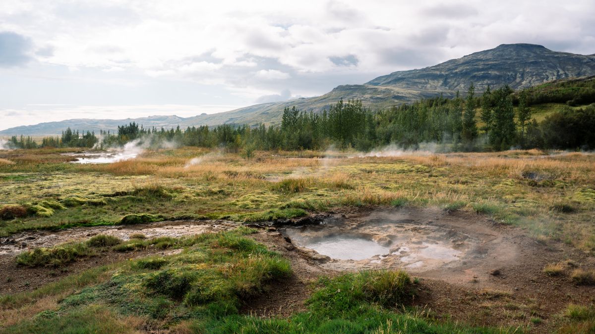 Jamaal Hutchinson / Pexels Scenic view of Icelandic hills and steaming hot springs under a cloudy sky.