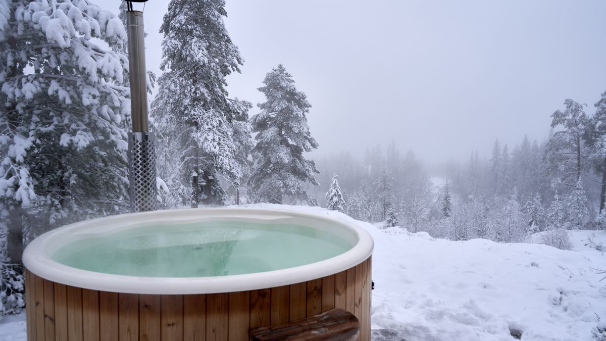 Relaxing hot tub amidst snow-covered trees in a serene Norwegian winter landscape.