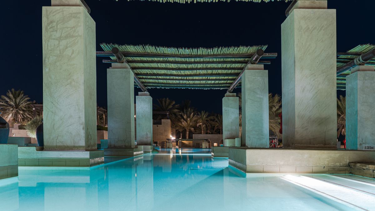 Stunning poolside view of a luxury hotel in Dubai by night, perfect for relaxation.