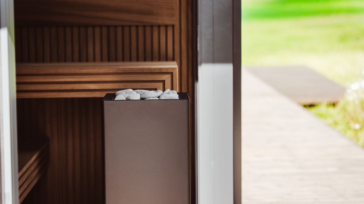 HUUM │sauna heaters / Pexels Contemporary outdoor sauna featuring wood panels and an electric heater with stones.
