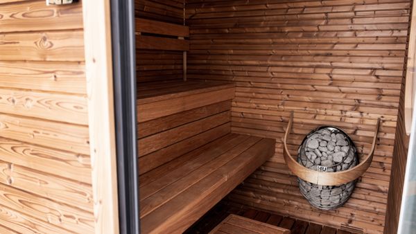 Explore a serene wooden sauna featuring Nordic design and modern electric heater for ultimate relaxation.