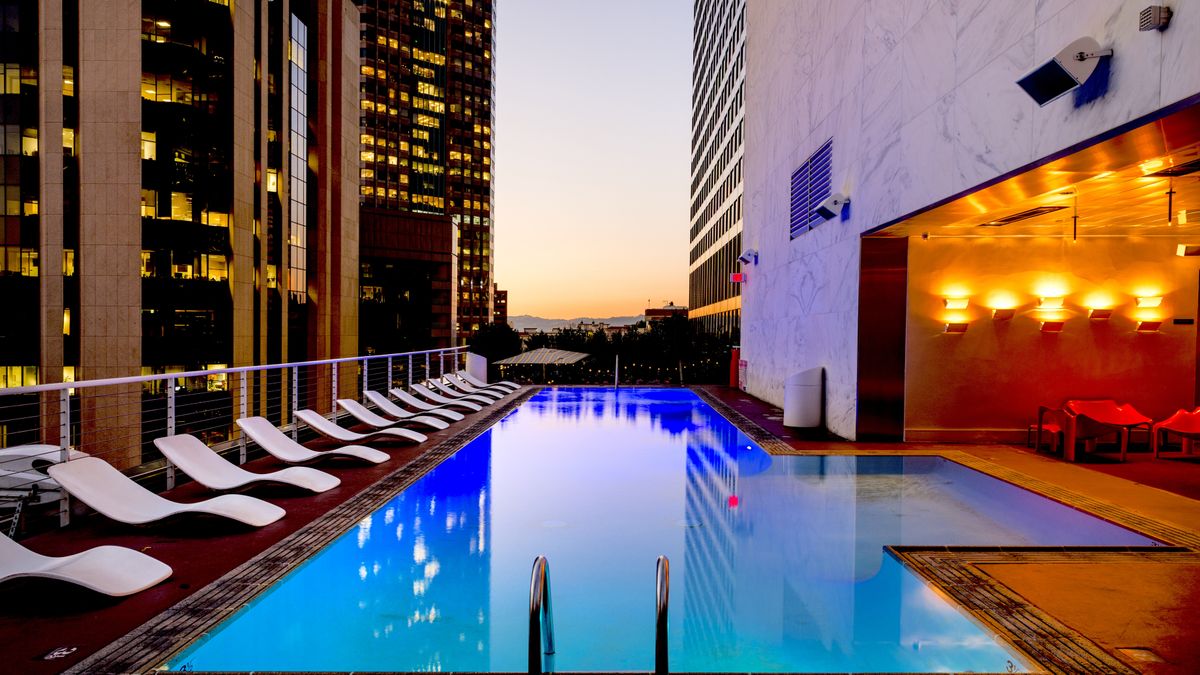 Elegant rooftop pool with cityscape backdrop at sunset, reflecting urban luxury.