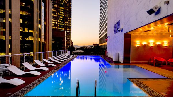 Elegant rooftop pool with cityscape backdrop at sunset, reflecting urban luxury.
