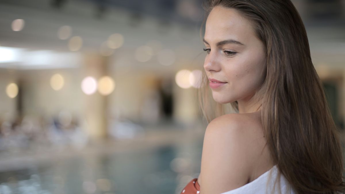Portrait of a woman relaxing indoors by the pool with soft lighting.