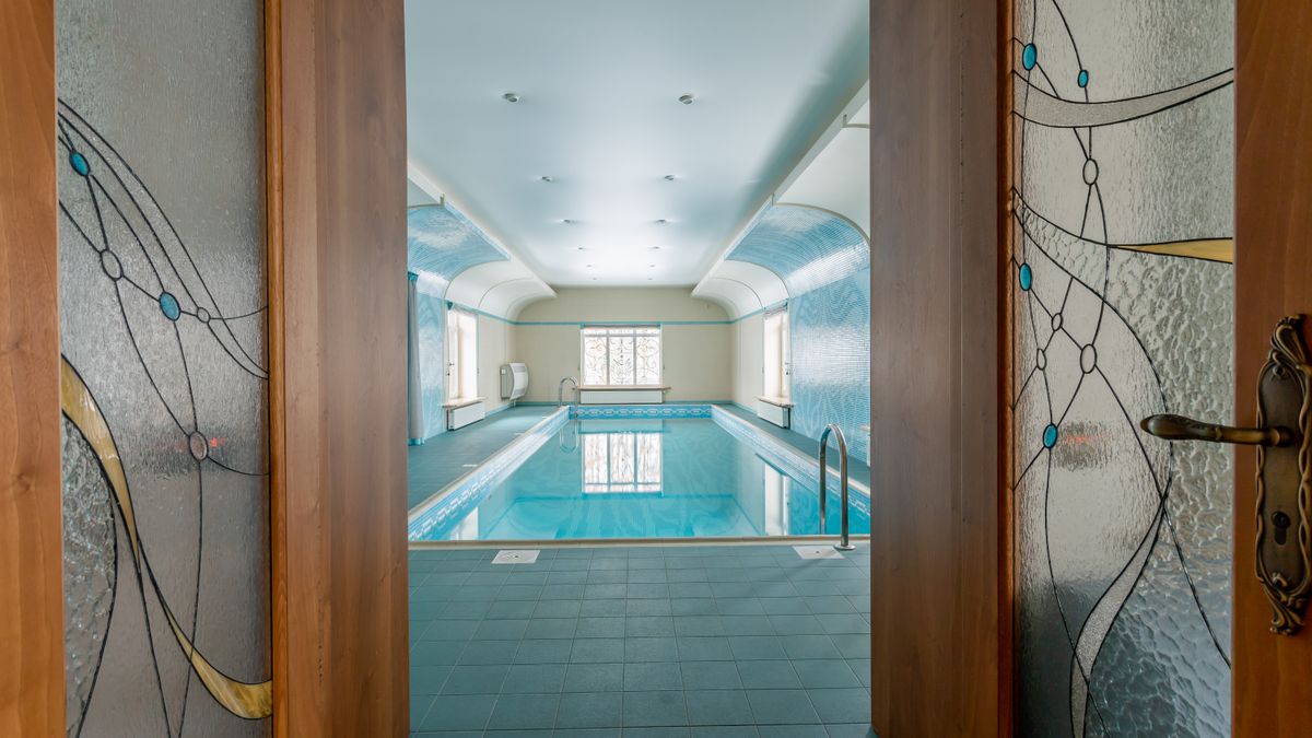 Elegant indoor swimming pool with stained glass doors, perfect for luxury relaxation.