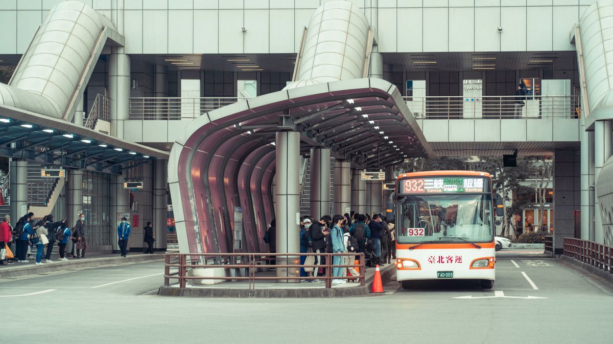 Public transport bus picking up commuters at a modern urban terminal with architectural features.