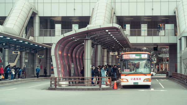 Public transport bus picking up commuters at a modern urban terminal with architectural features.