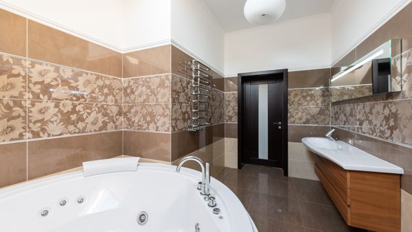 Interior of contemporary bathroom with round ceramic bathtub and sink and wooden cabinet in daytime