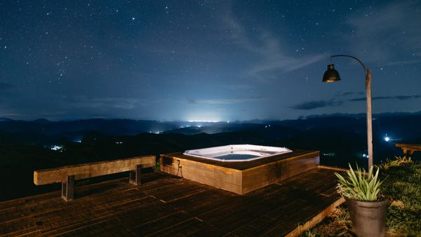 Relaxing outdoor jacuzzi under a starry sky with distant city lights in Santa Teresa, Brazil.