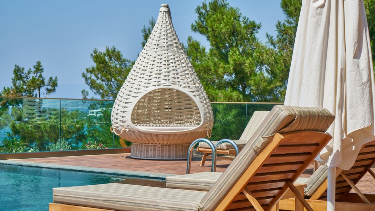 Elegant poolside setting featuring modern loungers and a unique woven chair in a tropical resort.