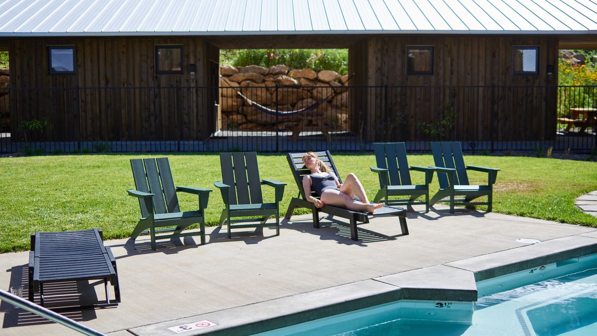 A woman in a swimsuit relaxes by the pool on a sunny summer day, enjoying leisure time.