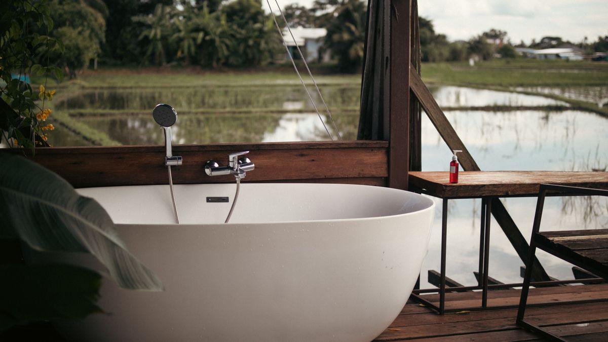 Relaxing outdoor bathtub setup with a scenic view of rice fields and lush greenery.
