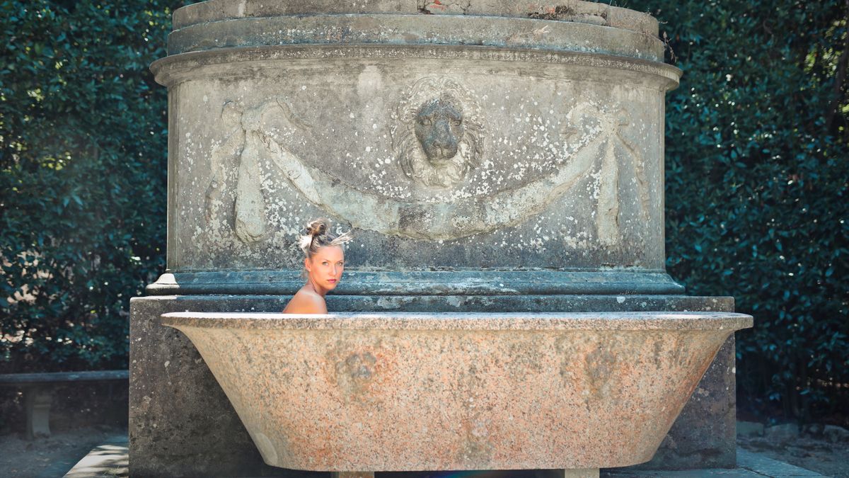 Andrea Piacquadio / Pexels A woman sitting in an antique bathtub with a historic stone background.