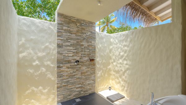Experience a refreshing outdoor shower amidst lush greenery in a tropical paradise.