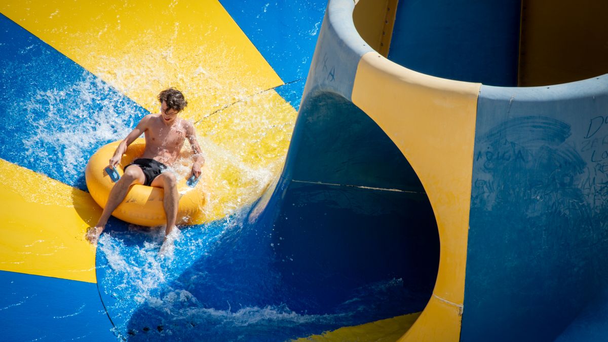 Teen enjoying a thrilling ride on a colorful waterslide at a water park.